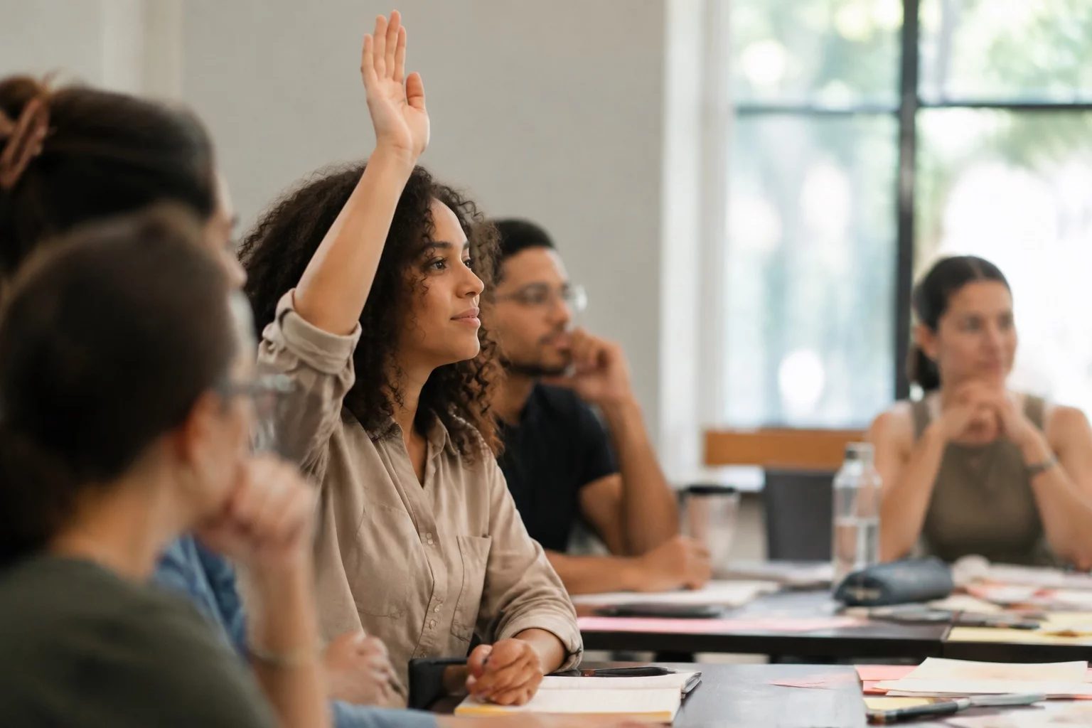 Estudante levantando a mão em uma mesa de seminário coberta de anotações